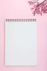 empty notebook and dry flower on pink background. flay lay style. home office workplace concept wiht copy space.