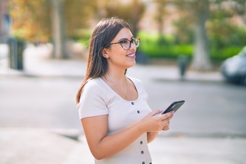 Young beautiful woman smiling happy and confident. Standing with smile on face using smartphone at the city