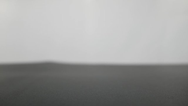 Crystal glass ball sphere transparent rolling on grey gradient background.