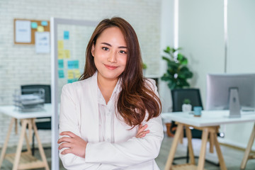 Portrait of Asian Businesswoman with Arms Crossed and standing at modern workplace