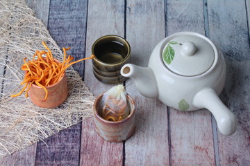 Golden cordyceps mushroom in cup ,herbal tea bag of  golden cordyceps militaris and a cup of tea served on wood
