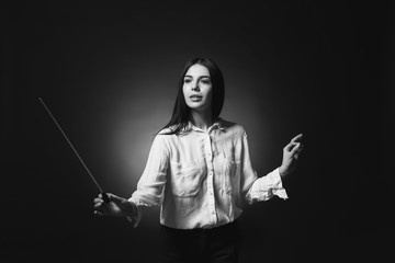 Black and white photo of young female conductor on dark background