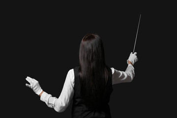 Young female conductor on dark background