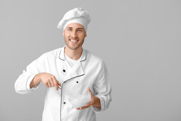 Male confectioner cooking tasty dessert on grey background