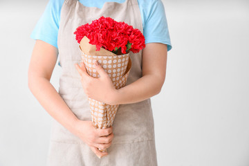 Female florist with beautiful bouquet of carnation flowers on light background