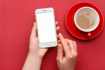 Female hands with mobile phone and cup of coffee on color background