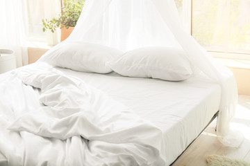 Big comfortable bed with clean linen in room © Pixel-Shot