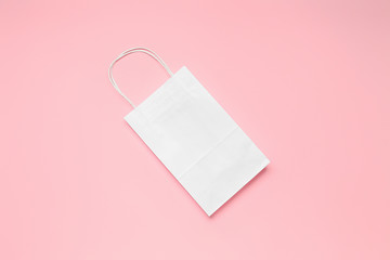 Paper shopping bag on color background