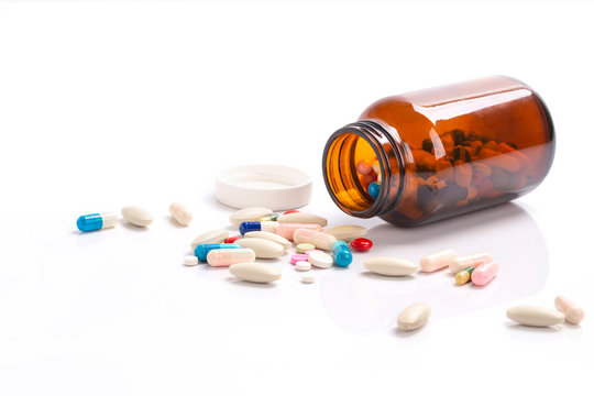 Closeup on pills capsules spilling out of pill bottle isolated on a background , Healthcare and medical drugs concept