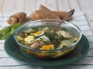 A bowl of spring natural green cabbage soup on a wooden table with home baked whole grain bread.