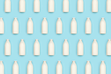 Pattern made with transparent glass bottle of milk on blue background. Flat lay Top view