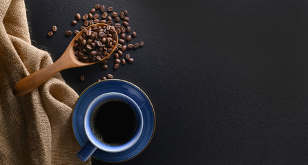 Top view of a cup of coffee and coffee beans on black background