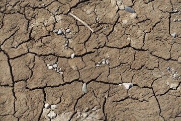 Cracked earth soil ground texture background. Mosaic pattern of dried mud clay earth and sand, top view. The concept of soil erosion climate change and sudden changes in air temperature.