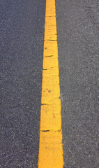 Close-up old yellow lines on an asphalt road-narrow
