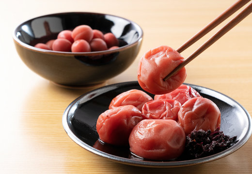 Two types of Japanese pickled plums set against a wooden background