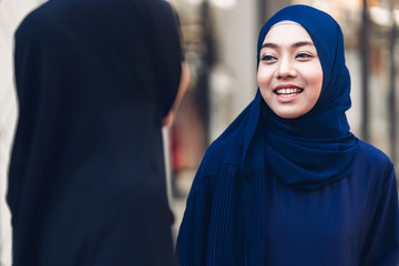 Portrait of happy arabic two friend muslim woman with hijab dress smiling and talking together at store