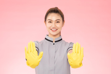 Attractive Beautiful Asian woman maid wearing gloves smile and open palm stop sign feeling so happiness and confident,Isolated on pink background,Cleaning Service concept