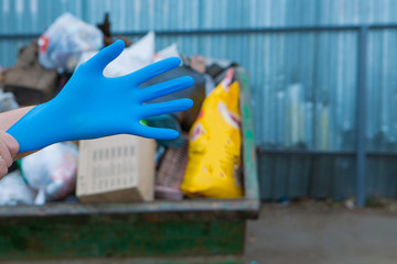 a man wears rubber gloves for garbage collection. a lot of garbage in the container. garbage collapse. Janitors ' strike. environmental disaster of plastic recycling. and close-up