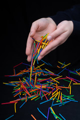 Hand letting coloured wooden  sticks drop on black