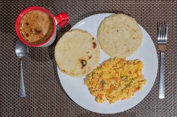 Typical colombian breakfast with criollo eggs, arepas and coffee