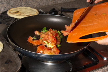 Green onion and tomatoes chopped on a cast iron. Home made colombian hogao or criollo sauce