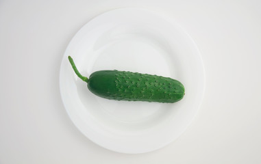 green cucumber on a white plate and white isolated background