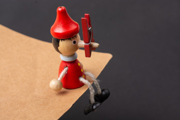 Wooden pinocchio doll with clothespin on his long nose