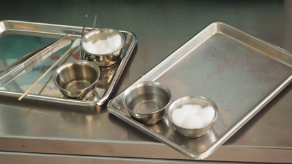 Wound care dressing set on stainless steel plate. White cotton ball, cotton stick, forceps.Selective focus.