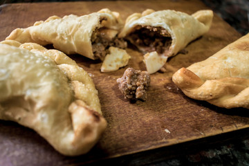 Argentine fried empanadas, served on wooden board.
