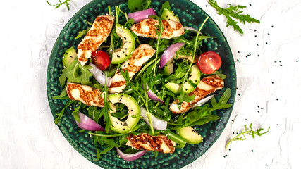 Keto food. National Cyprus Salad with grilled Halloumi cheese, tomatoes, avocado, arugula. Detox and healthy concept. Overhead, top view, banner