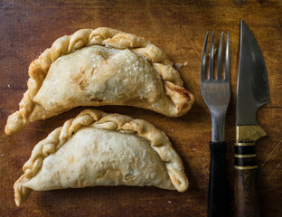 Argentine fried empanadas, served on wooden board.