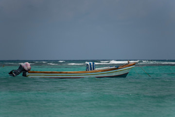 Boat floating in a beautiful turquoise blue water caribbean beach in a sunny day with blue sky