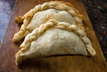 Argentine fried empanadas, served on wooden board.