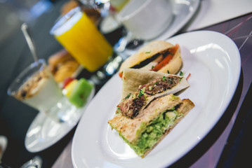 Delicious brunch type breakfast at coffee break in seminar in hotel with little sandwiches, orange juice and dessert