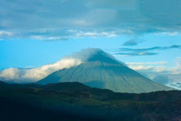 Fototapeta premium Volcano covered with clouds in Guatemala, forest landscape at imposing sunset on the horizon.