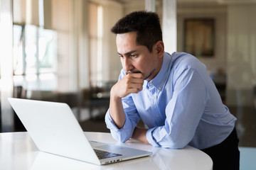 A young businessman using laptop standing working with happy in modern office.