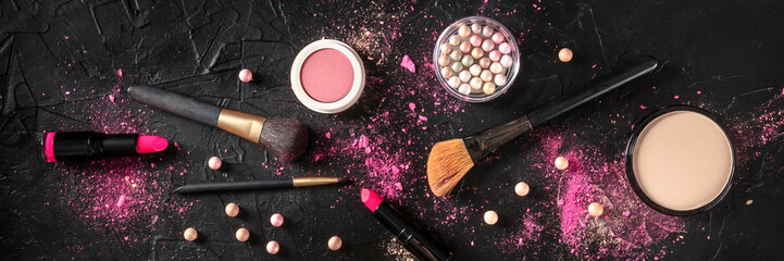 Professional makeup panorama on a dark background. Brushes, lipstick and other products, a flat lay