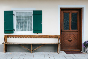 Brown door and green shuttered window of a traditional mountain hut in the Bavarian alps.
