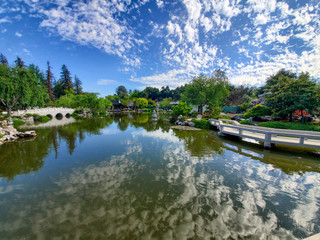 April 2019, California: Beautiful cloud reflections off the lake water in landscaped gardens with beautiful flowers, bushes, trees, bridges and buildings in southern California
