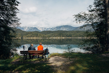 An elderly couple sit on a bench after walking round the lake. Eibsee, Garmisch-Partenkirchen, Bayern, Germany