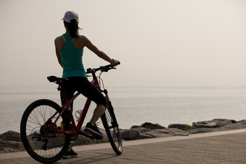 Woman cyclist riding mountain bike on seaside