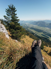 Legs of a male hiker hanging over the edge of a mountain over the Inntal valley. Tirol, Austria