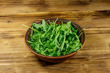 Fresh green arugula in ceramic bowl on a wooden table. Healthy food or vegetarian concept