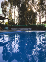 Sunrise, sun and trees over the water of a big and blue pool between the nature with reflections