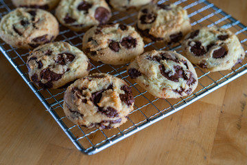 Homemade baked chocolate chip soft cookies cooling on a cooling rack. On a wooden background. Natural light.