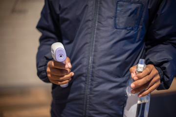 Cropped shot of officer holding hand sanitizer and infrared thermometer in hand