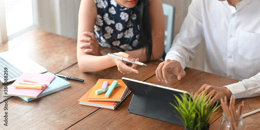 Poster cropped image of business developer team working together with computer tablet and note while sittin