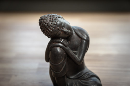 Buddah sculpture on desk - miniature buddah statue on desk - concept image for mediation, mindfulness, relaxation, isolation, philosophy