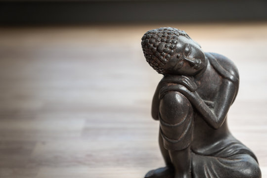 Buddah sculpture  - miniature buddah statue on desk - concept image for mediation, mindfulness, isolation, relaxation, philosophy