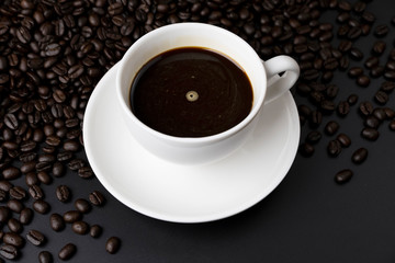 Obraz na płótnie Canvas Hot black coffee in a white coffee cup on coffee beans field background